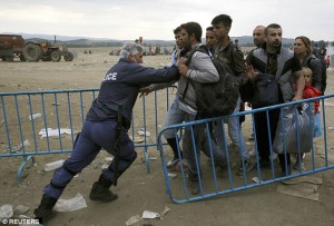 A_policeman_pushes_refugees